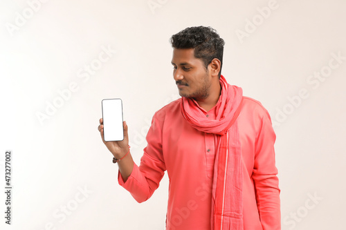 Young indian farmer showing smartphone and giving expression on white background.