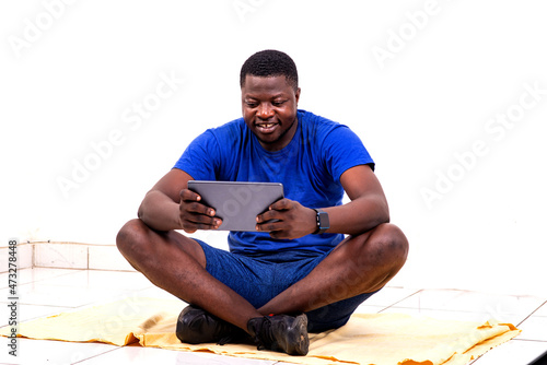 young sporty man sitting using a digital tablet smiling.