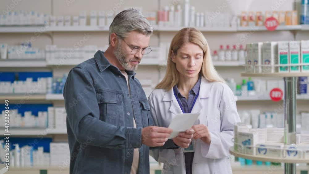Caucasian adult handsome man having consultation talk with female pharmacist. Apothecary woman worker advising healthcare product to customer. Selling medicine. Caucasian adult handsome man having consultation talk with female pharmacist. Apothecary woman worker advising healthcare product to customer. Selling medicine.