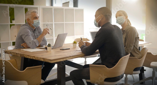 team working in an office wearing covid-19 pandemic masks