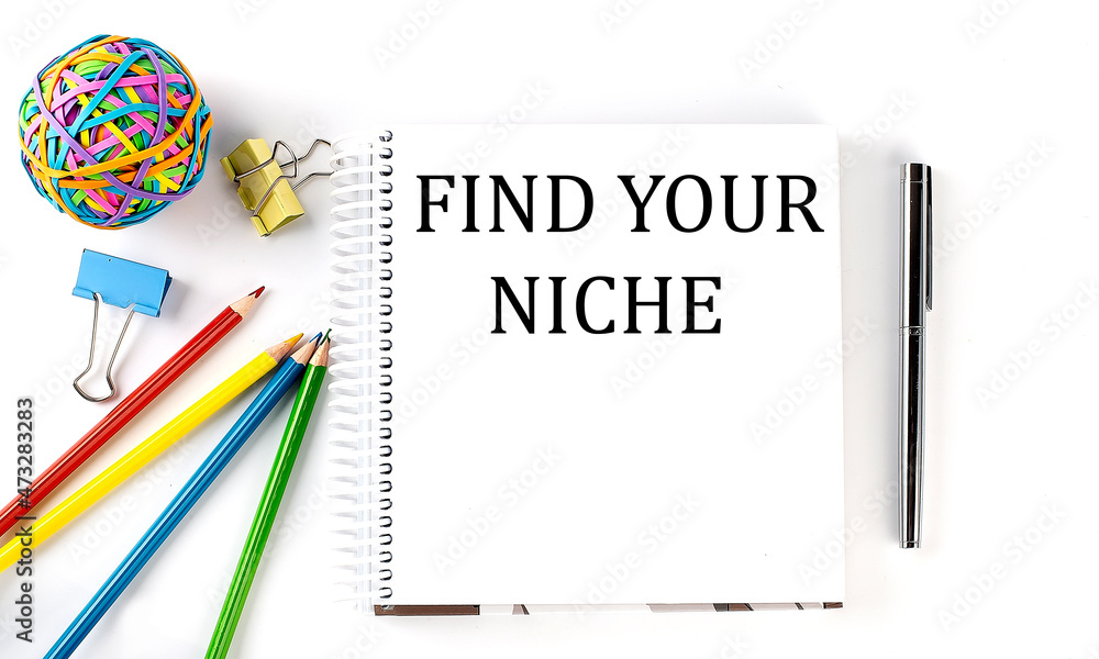 Notebook ,pencils,pen and rubber band with text FIND YOUR NICHE on the white background Notebook ,pencils,pen and rubber band with text FIND YOUR NICHE on the white background