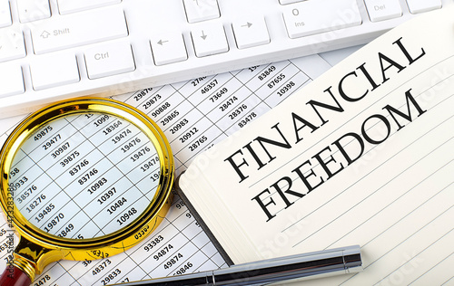 FINANCIAL FREEDOM text on the notebook with chart, magnifier,keyboard and pen
