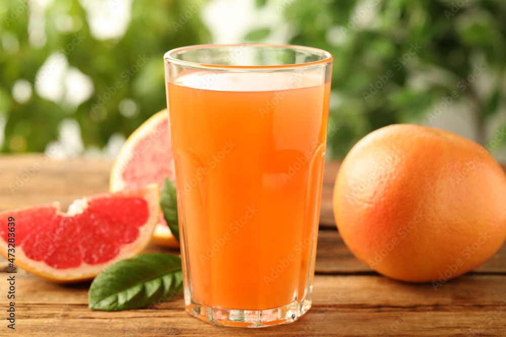 Glass of delicious grapefruit juice on wooden table against blurred background Glass of delicious grapefruit juice on wooden table against blurred background
