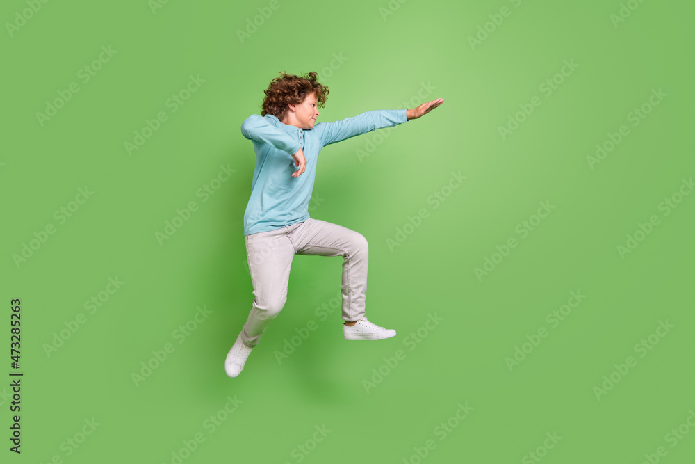 Full length body size view of attractive guy jumping dancing fighting fooling isolated over bright green color background Full length body size view of attractive guy jumping dancing fighting fooling isolated over bright green color background