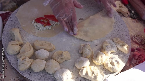 Adult woman making chebureks - roasts chebureks in pan, prepares meat pies, working with the dough and filling, close-up. Fried flatbread piadina naan pita tortilla shelpek cheburek. Street food. photo