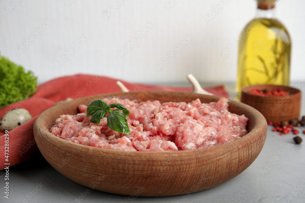 Raw chicken minced meat with basil on grey table
