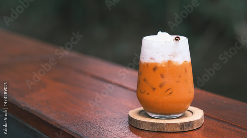 Thai Milk Tea, Milk ice tea, Cheddar is a traditional Thai drink that has long been popular, fresh and sweet dessert on a wooden saucer, vintage wooden table in cafe. photo