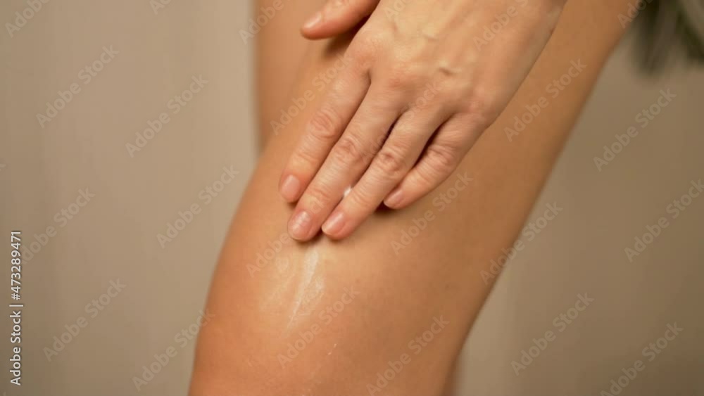 Woman Rubs Nourishing Cream into Thigh and Massages the Leg, Close-up, Slow Motion. Body Skin Care Concept. Woman Rubs Nourishing Cream into Thigh and Massages the Leg, Close-up, Slow Motion. Body Skin Care Concept.