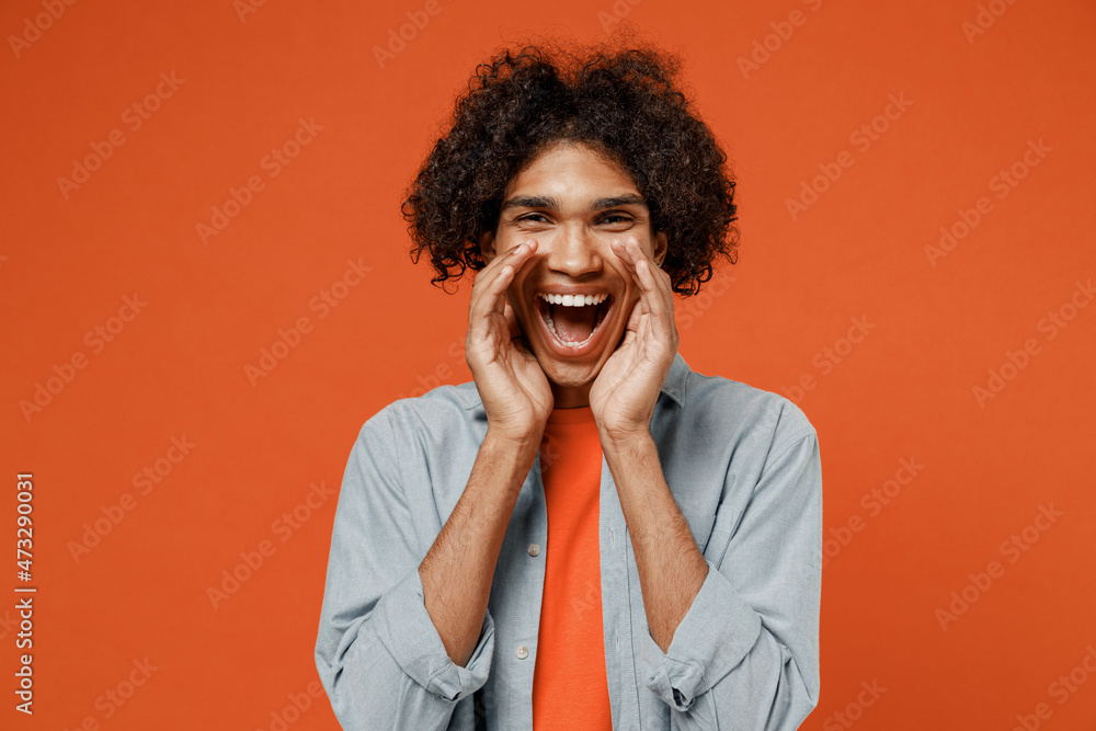 Young promoter black man 50s wearing blue shirt t-shirt scream hot news about sales discount with hands near mouth isolated on plain orange color background studio portrait. People lifestyle concept.