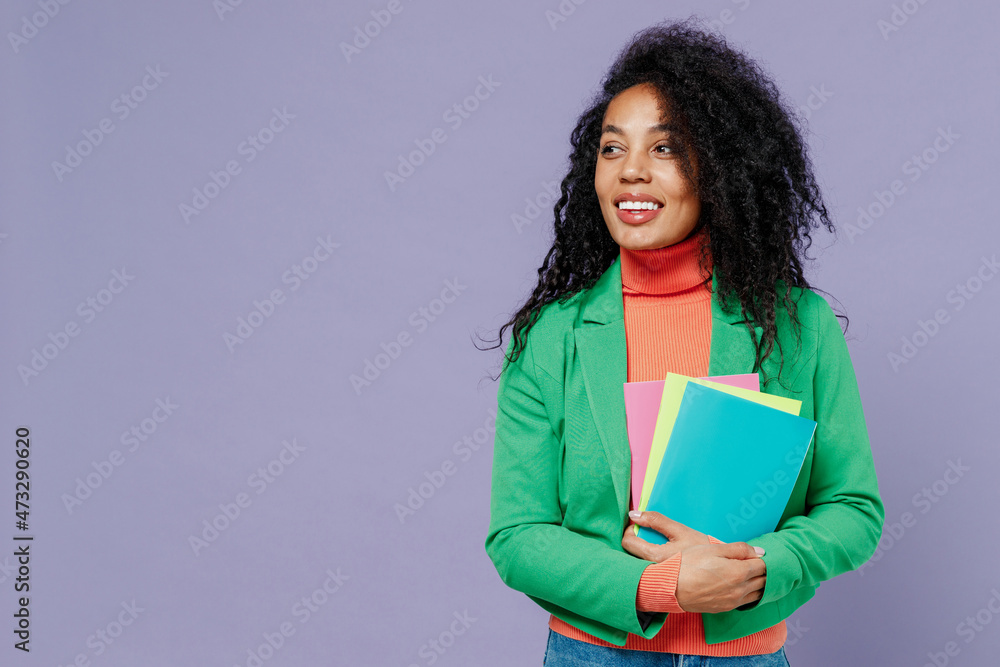 Obraz premium Teacher smiling elegant charismatic fun young black curly woman 20s wear green shirt looking aside holding in hands coloured textbooks isolated on plain pastel light violet background studio portrait