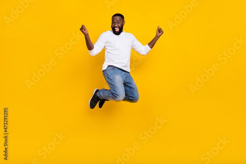 Full body portrait of delighted guy raise fists celebrate success achievement isolated on yellow color background