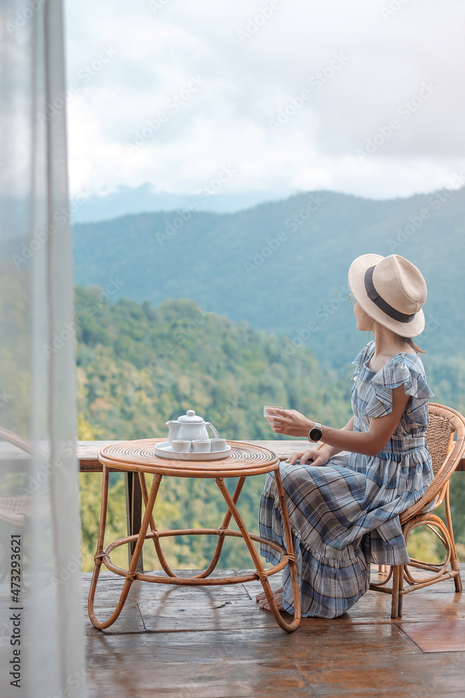 woman drinking tea and looking mountain view, young blogger stay at countryside homestay in the morning.Travel, vacation, journey, trip and relaxing concept