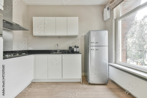 Modern furnished kitchen interior with wide window and fridge photo