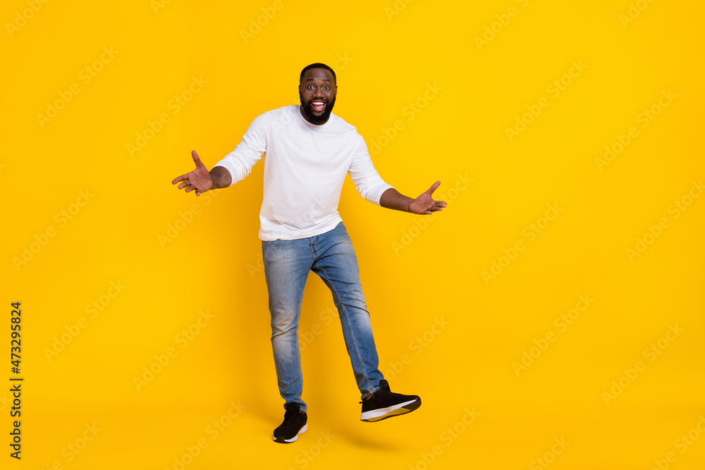 Full body photo of satisfied carefree person arms palms enjoy free time toothy smile isolated on yellow color background Full body photo of satisfied carefree person arms palms enjoy free time toothy smile isolated on yellow color background