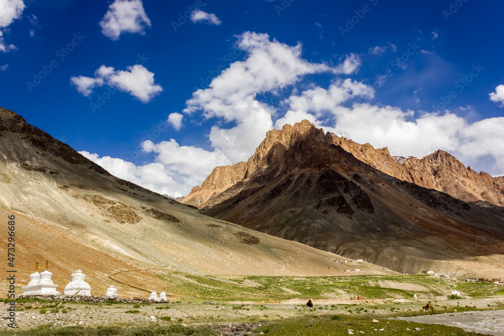 Beautiful landscape of barren mountains against the blue sky with Tibetan Buddhism chortens on a trekking trail in Zanskar in Ladakh in the Indian Himalaya.