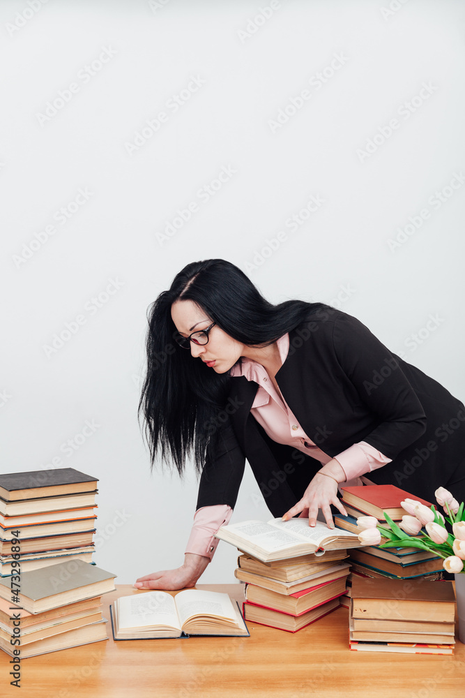 female teacher at a table with books for teaching female teacher at a table with books for teaching