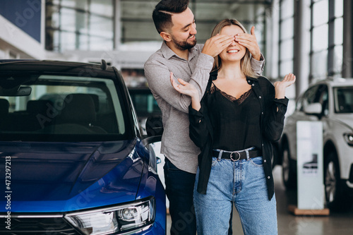Young couple choosing a car in a car show room