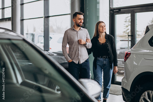 Young couple choosing a car in a car show room