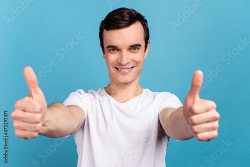 Photo of young handsome man show fingers thumbs-up ad promo suggest isolated over bright blue color background © Tetiana