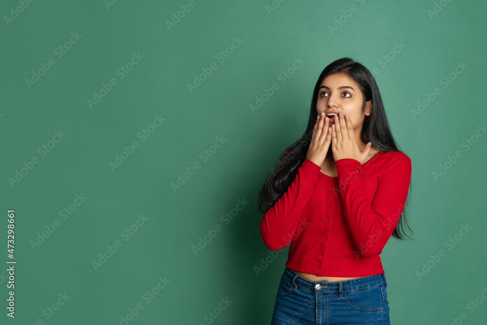 Studio shot of young adorable cute girl, student in casual style clothes posing isolated on dark green studio backgroud Studio shot of young adorable cute girl, student in casual style clothes posing isolated on dark green studio backgroud