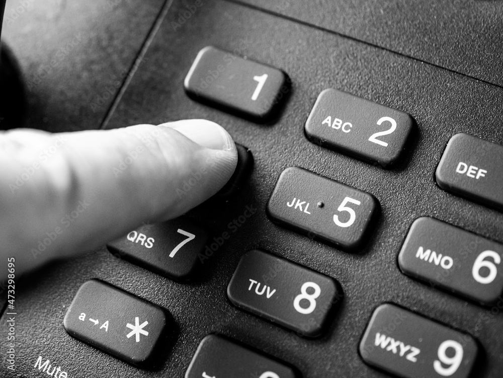 Finger pressing the number 4 on a phone keypad, black and white image Finger pressing the number 4 on a phone keypad, black and white image
