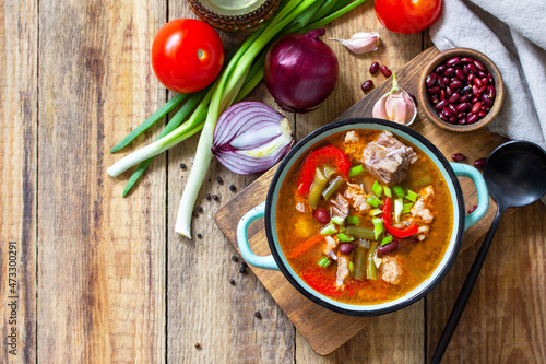 Traditional English thick soup with beef  beans and vegetables on a wooden table. Hot dinner or lunch. Top view flat lay. Copy space.