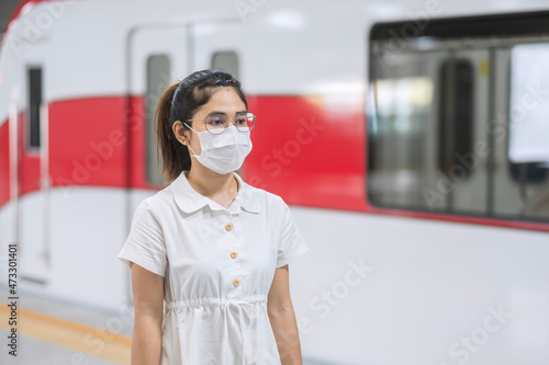 woman wearing Protective face mask prevention coronavirus inflection during waiting train. public transportation. social distancing, new normal and safety under covid-19 pandemic photo