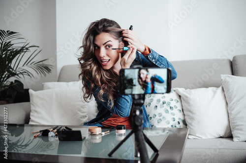 Influencer applying mascara at home studio photo
