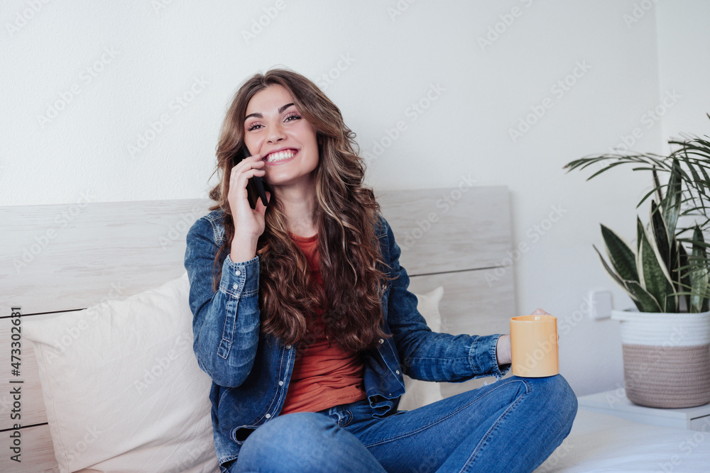 Happy woman with long hair talking on mobile phone in bedroom Happy woman with long hair talking on mobile phone in bedroom