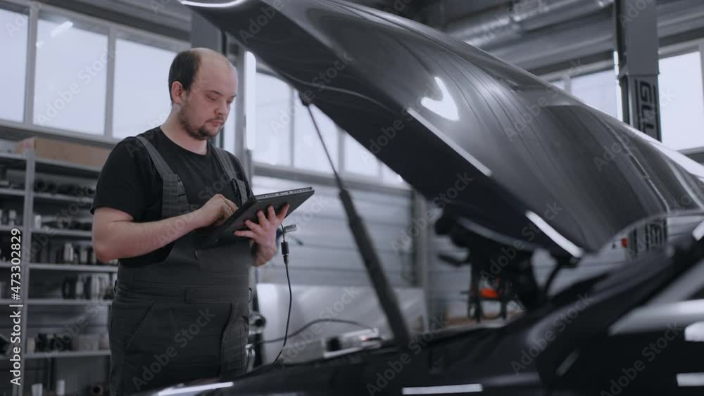Diagnostics of the car at the hood in the car service with a tablet. Mechanic Diagnostics of the car at the hood in the car service with a tablet. Mechanic