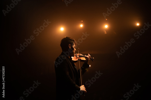 Konstfotografi WIDE young aspiring musician playing violin on a stage of a large venue