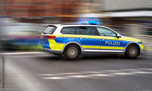 German police emergency vehicle with blue lights on speeds through an intersection, intentional motion blur of background © Frank