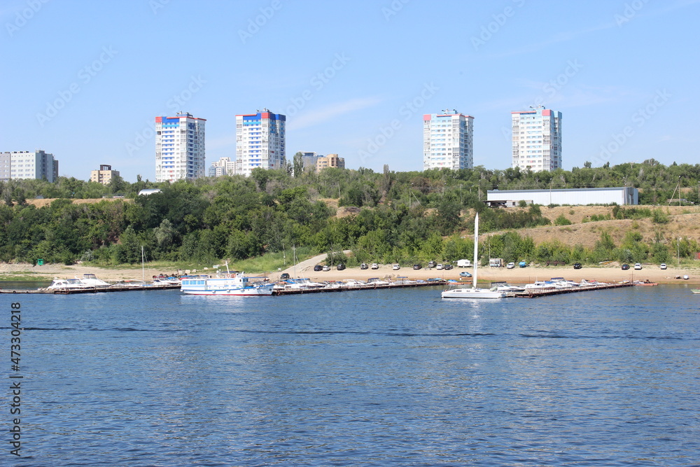 Volga River, a suburb of Volgograd. Berths and boats along the shore, high-rise buildings in the distance.