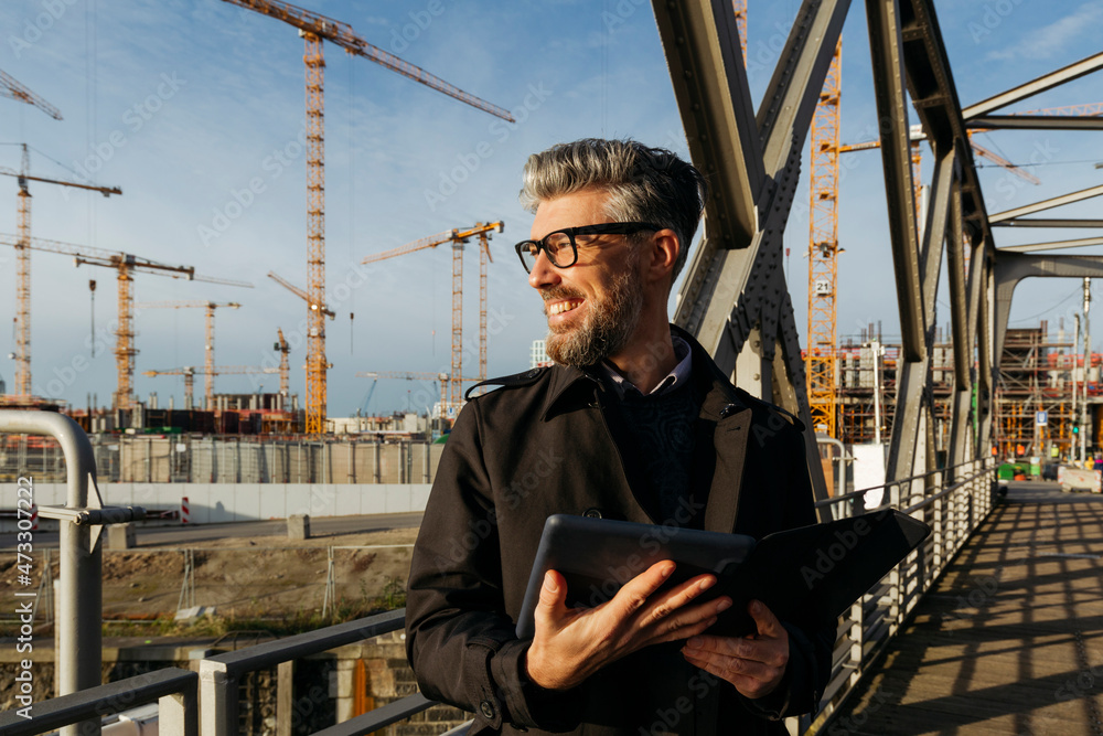 Smiling businessman with tablet PC on bridge Smiling businessman with tablet PC on bridge