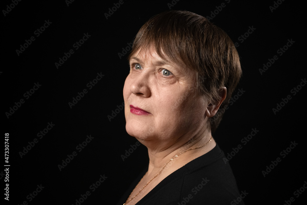Grandmother with a serious look in a black T-shirt on a black background. Grandmother with a serious look in a black T-shirt on a black background.