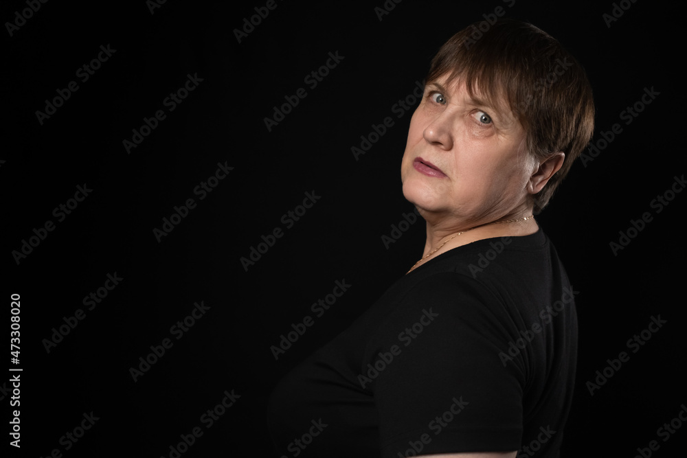 Grandmother with a serious look in a black T-shirt on a black background. Grandmother with a serious look in a black T-shirt on a black background.
