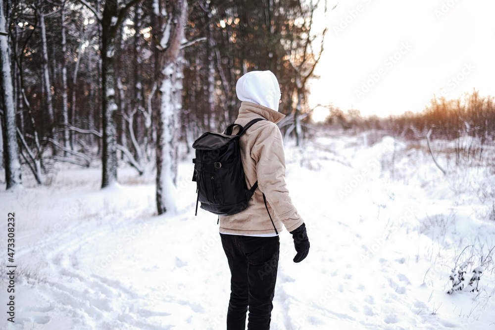 a man walks alone in the winter forest. a tourist with a backpack walks through the snow-covered coniferous forest a man walks alone in the winter forest. a tourist with a backpack walks through the snow-covered coniferous forest