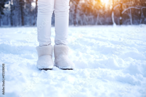legs of a woman in fur boots on the snow in the forest. girl in warm shoes walks through the snowy forest. warm fur winter shoes