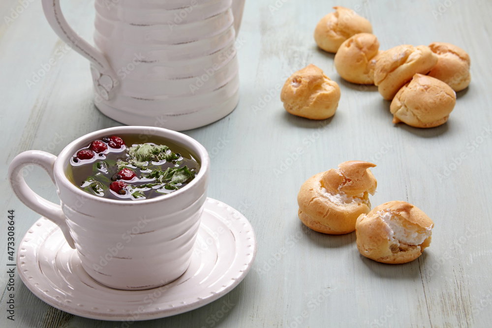 Appetizing profiteroles with whipped cream and a cup of herbal tea Appetizing profiteroles with whipped cream and a cup of herbal tea