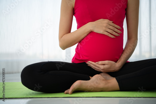 A pregnant woman meditates in a living room.