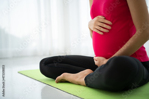 A pregnant woman meditates in a living room.