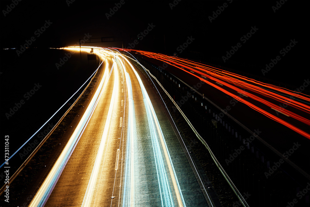 Moving cars at night on highway, long exposure. Motion blur effect of light trails. Fast speet traffic