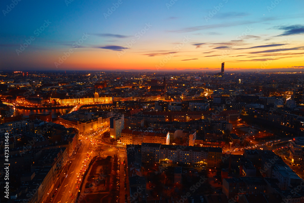 Aerial view of night cityscape. Wroclaw panorama at sunset with glowing streets and dramatic sunset sky