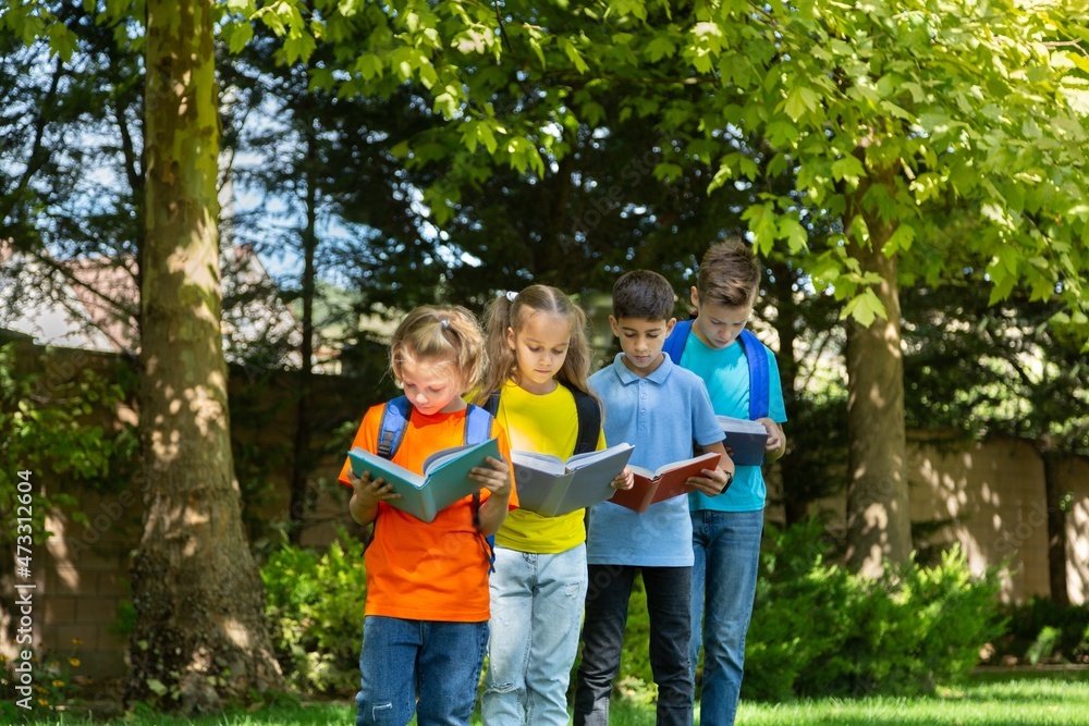 Fototapeta premium Group of happy school child with book in outdoor park