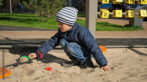 Little boy playing in sandpit on palyground and building sand castle. Concept of child development, sports and education. photo
