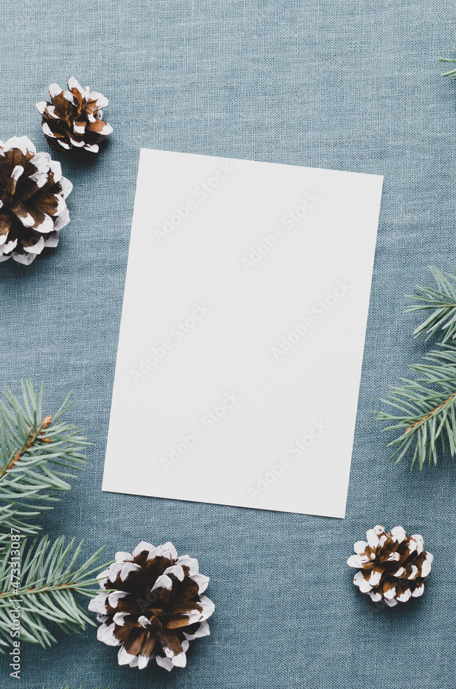 Christmas greeting card mockup with fir tree branches and cones on textile background Christmas greeting card mockup with fir tree branches and cones on textile background
