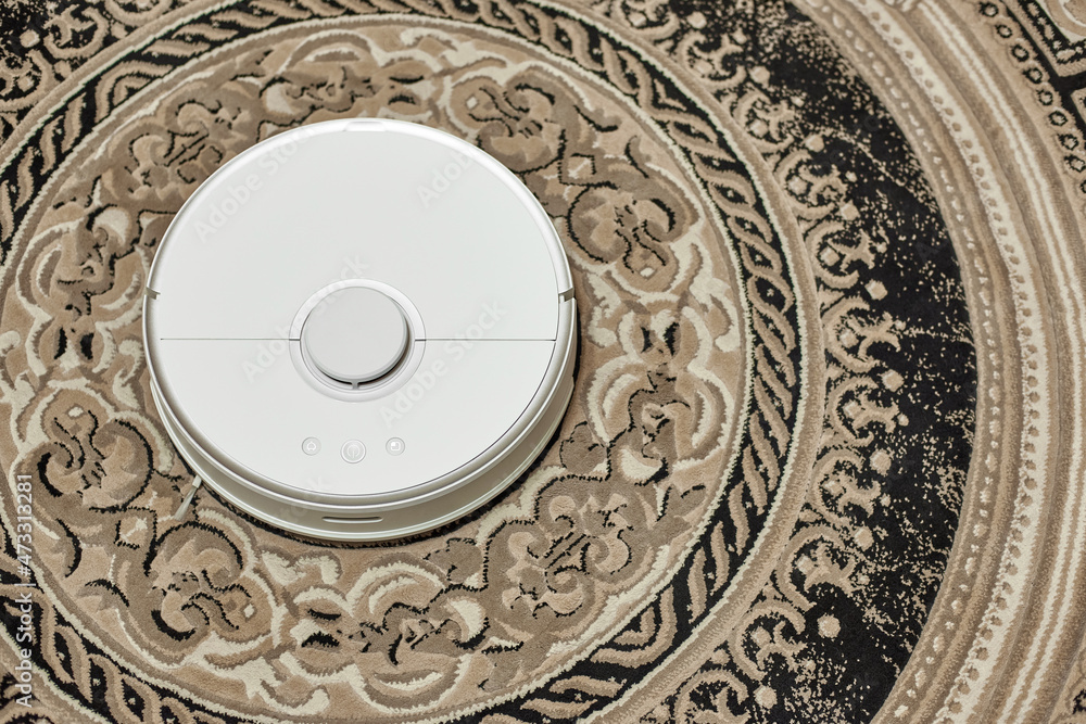 Robotic vacuum cleaner working on a round carpet. View from above.