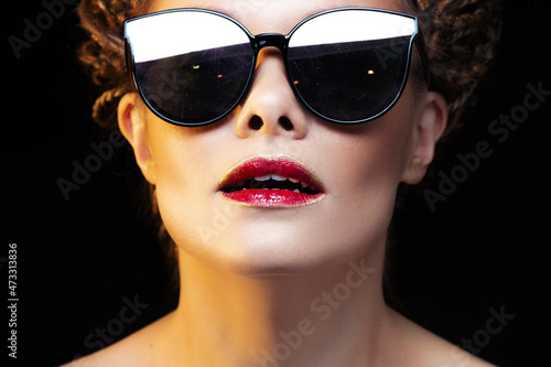 Beautiful joyful young woman in sunglasses. Bright lips with red lipstick  portrait on black