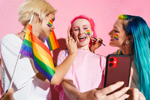 Young three women taking selfie while making rainbow makeup