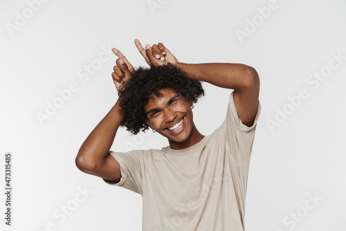 Young black man with piercing winking and making horn gesture